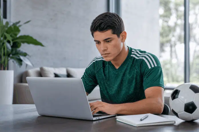 Joven futbolista mexicano estudiando en línea con una computadora portátil en un ambiente moderno y luminoso